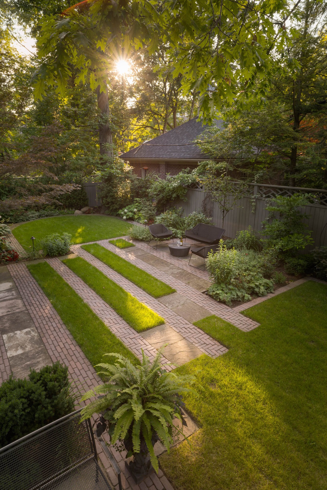 A serene garden with geometric paths, lush greenery, and cozy seating. Sunlight filters through leaves, creating a peaceful, inviting atmosphere.