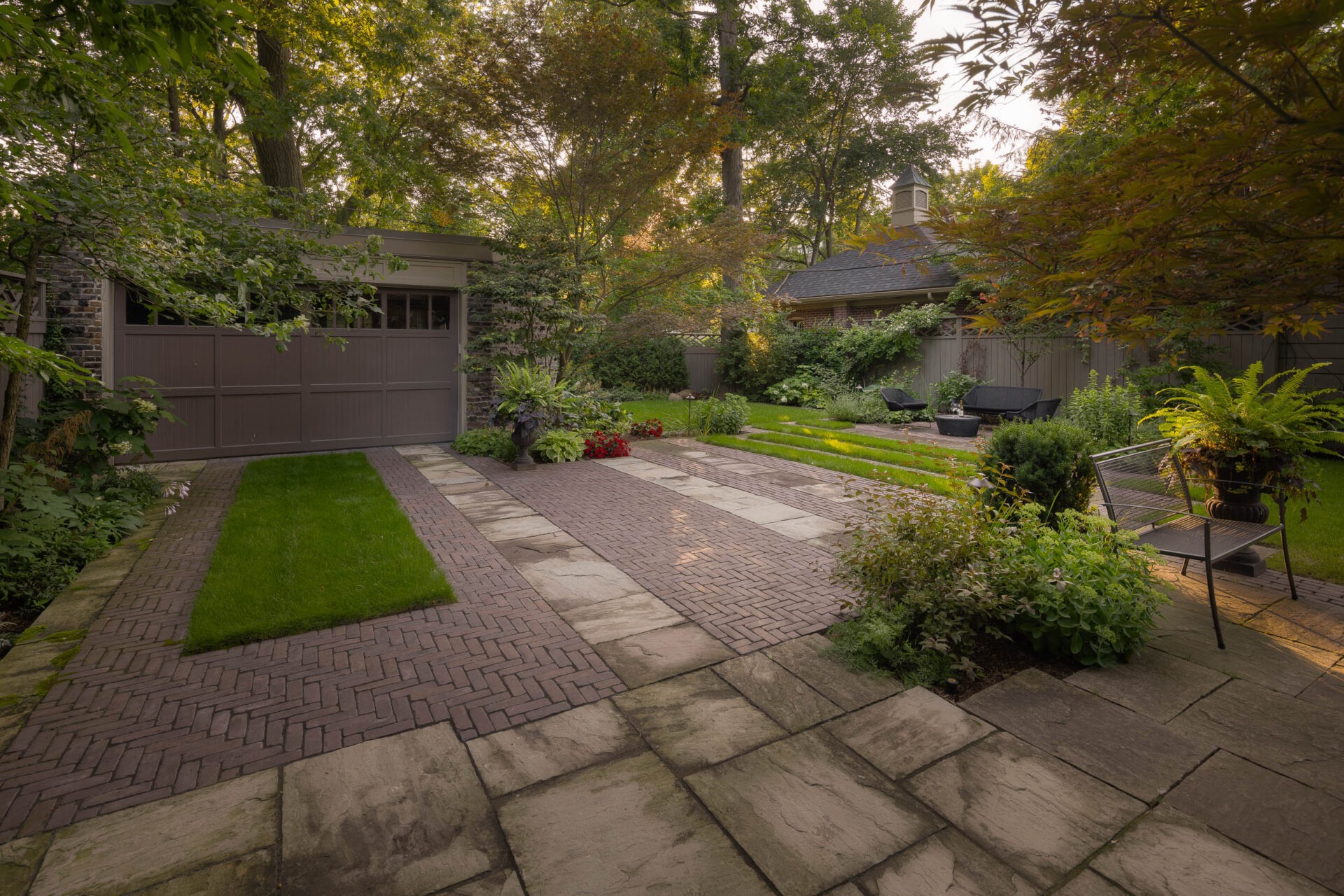 A serene garden features neatly arranged stone pathways, lush greenery, potted plants, and comfortable outdoor seating, creating a peaceful backyard retreat.