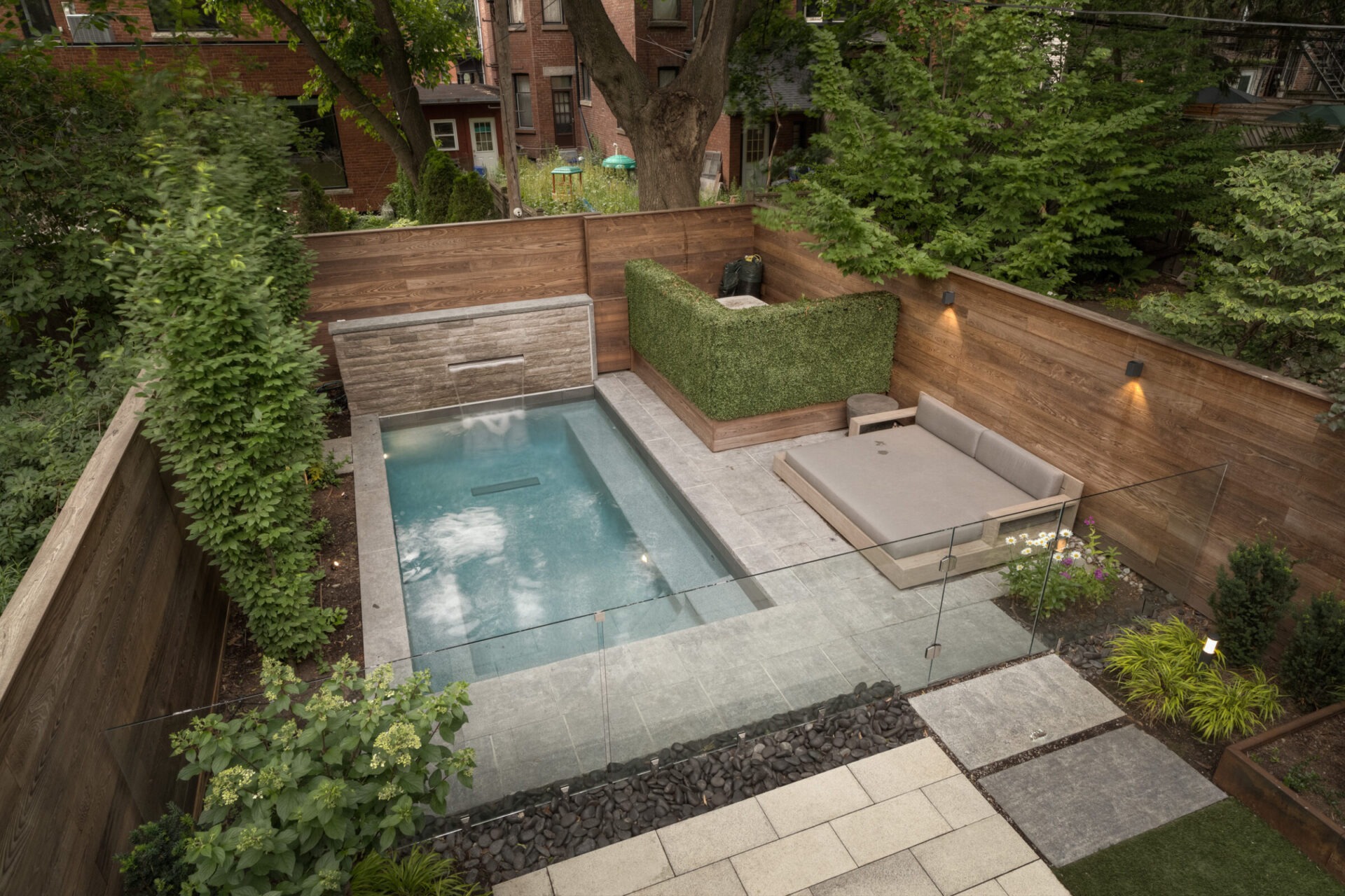 Cozy backyard features a small pool, modern seating area, and lush greenery enclosed by wooden fencing, offering a serene urban oasis.