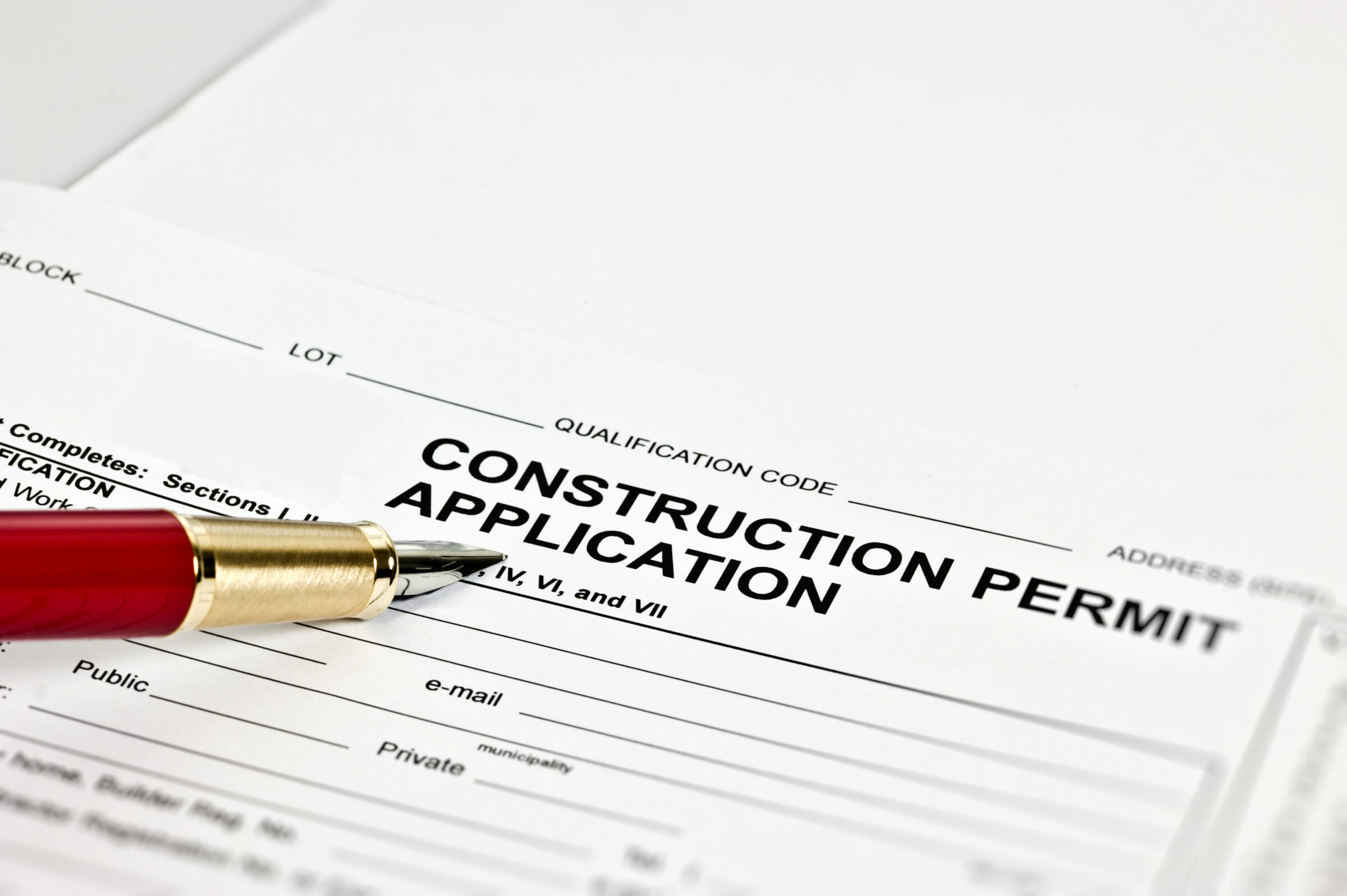 A construction permit application form with a red and gold pen placed on top, ready for filling out details and submission.