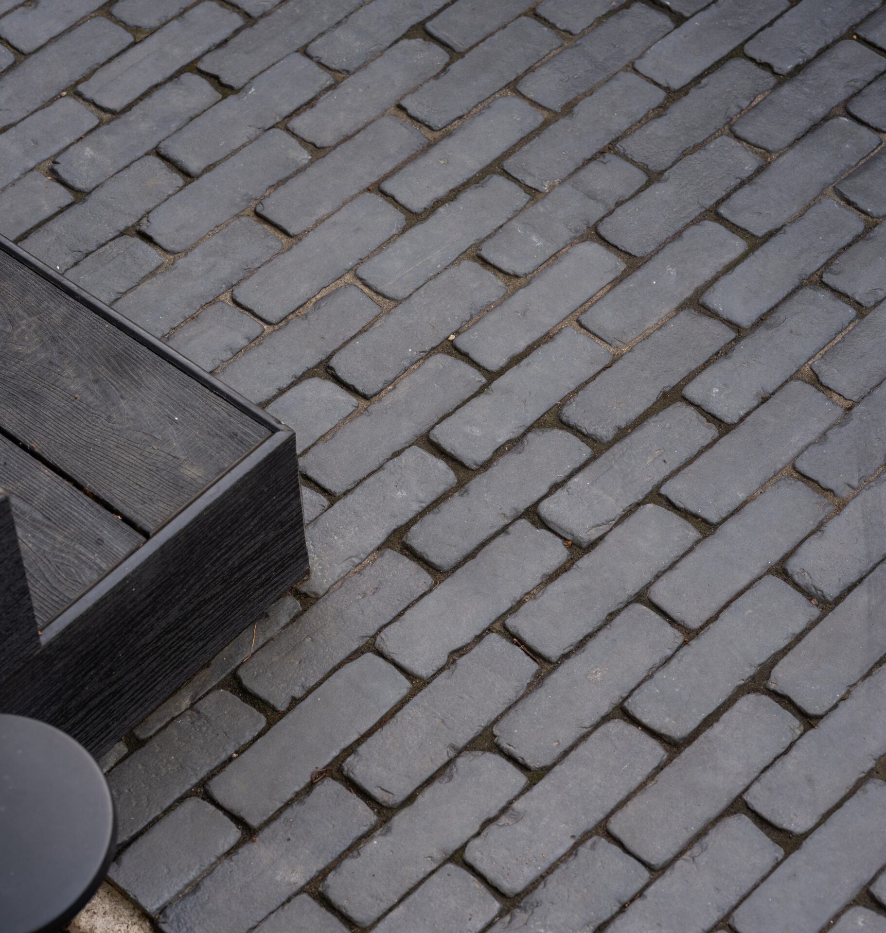 Cobblestone pavement with dark wooden furniture edges visible. No people or landmarks are present. Scene emphasizes textures and materials.
