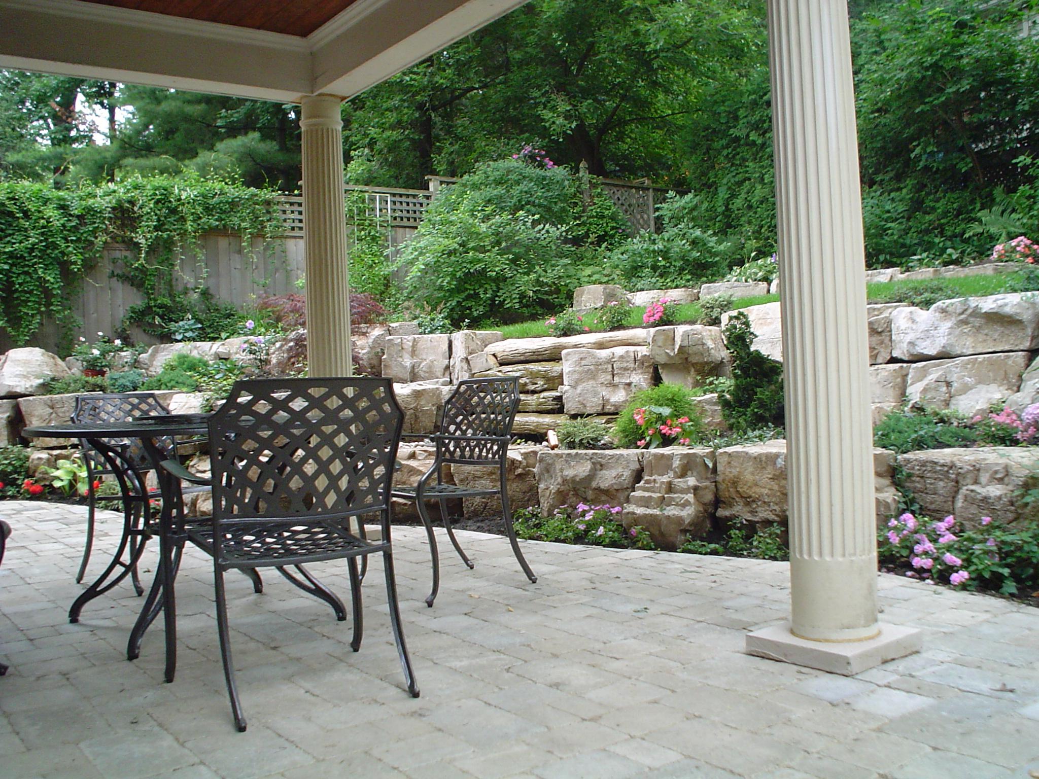 Covered patio with interlocking pavers and natural stone retaining wall