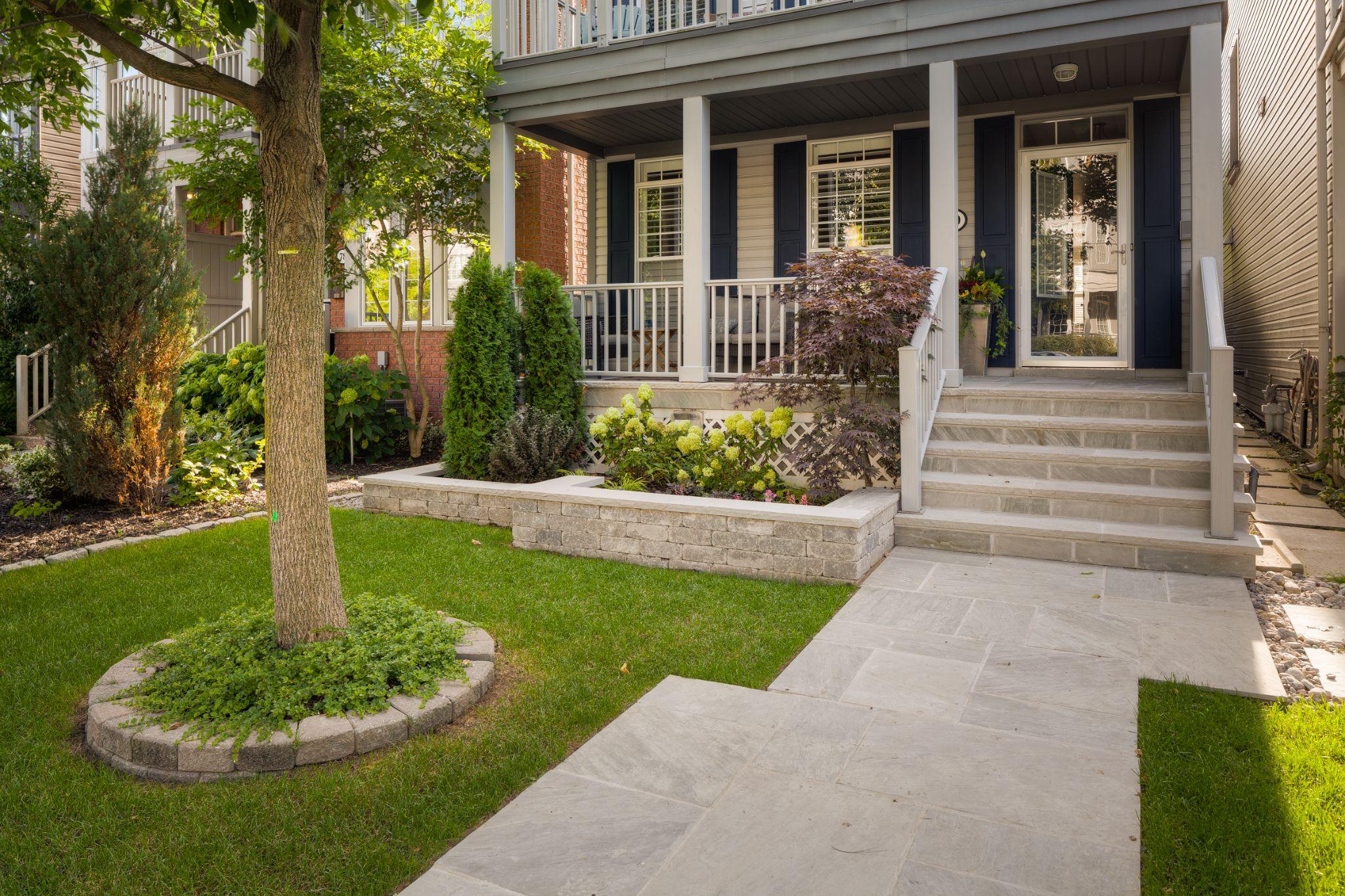 Front walkway with stone steps, raised planter, and porch entry