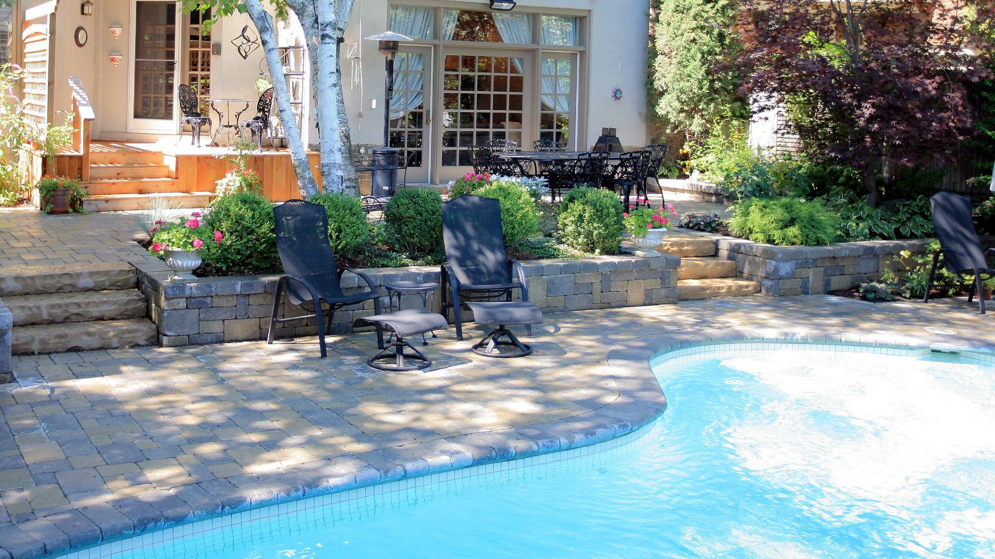 Stone pool deck with seating and raised garden walls
